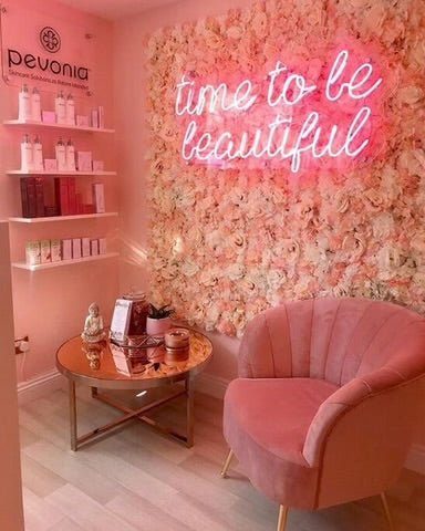 Неоновая надпись Time to be beautiful на стене из живых цветов в салоне красоты