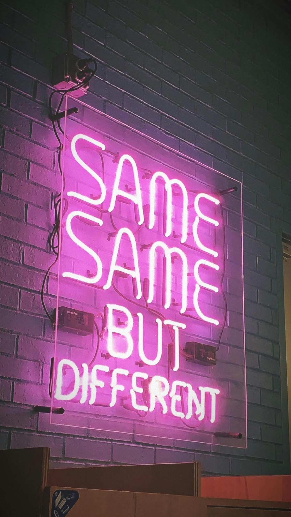 Неоновая надпись Same Same But Different на кирпичной стене — дерзкий слоган заведения