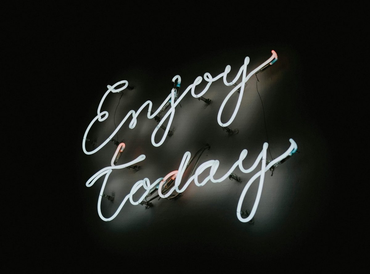 Неоновая надпись Enjoy Today на тёмном фоне — идеальная фотозона