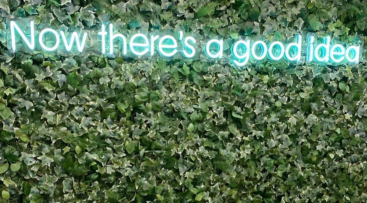 Неоновая надпись Now there's a good idea на зелёной стене из растений в офисе