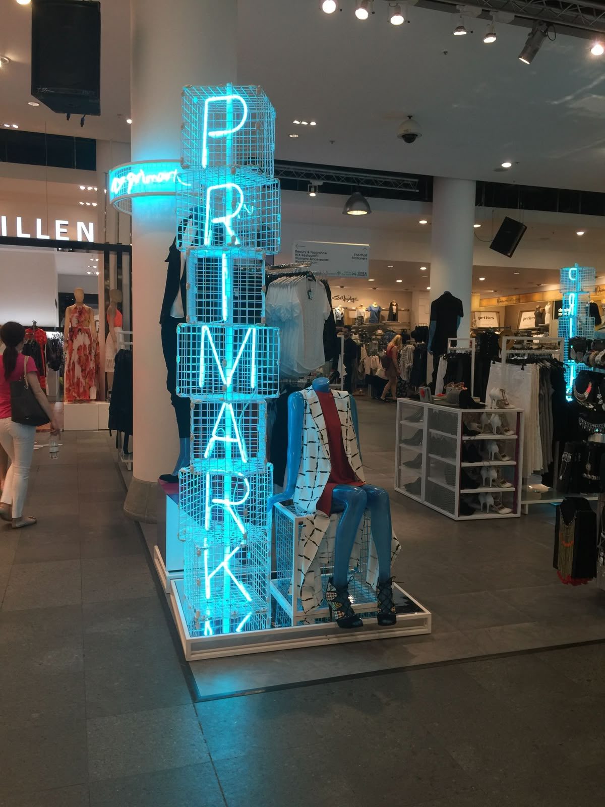 Неоновый логотип Primark бирюзовым неоном вертикально в зале торгового центра