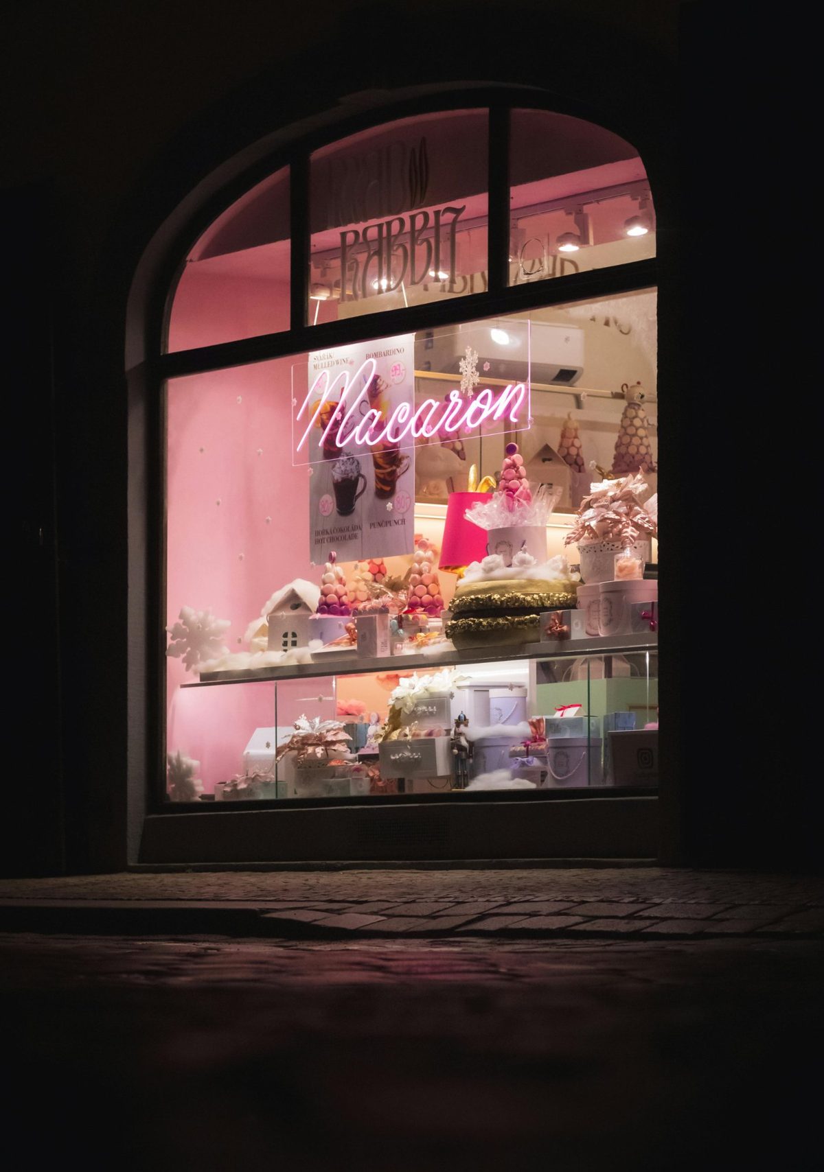 Неоновая надпись Macaron розовым неоном в витрине кондитерской ночью