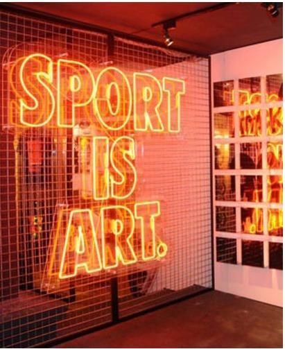 Неоновая надпись Sport Is Art оранжевым неоном на металлической сетке