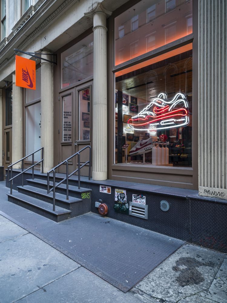 Неоновый кроссовок Nike красно-белым неоном в витрине магазина обуви на улице