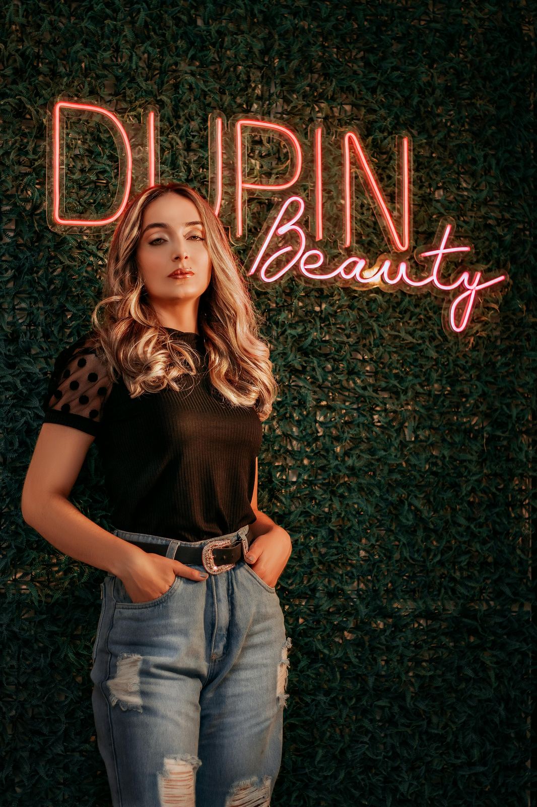 Неоновый логотип Dupin Beauty на зелёной стене из растений — фотозона в салоне